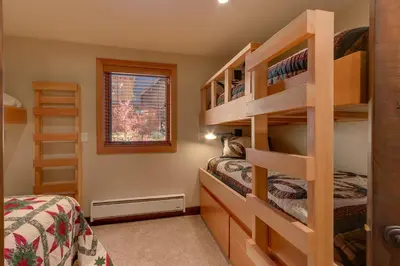 a bedroom with two beds and a bunk bed at Gray Bear Lake View Estate - Stunning Cabin w 4 Master Suites, Private Hot Tub! in Carnelian Bay