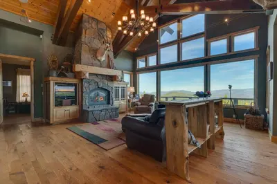a living room with a large fireplace and a couch at Grand Vista Lodge by Tahoe Getaways - 5 BR with Stunning Views, Pool Table, Private Hot Tub & HOA Pool! in Truckee