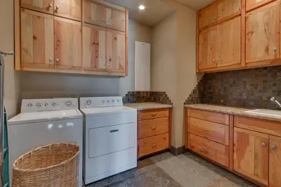 a kitchen with a washing machine and wooden cabinets at Grand Vista Lodge by Tahoe Getaways - 5 BR with Stunning Views, Pool Table, Private Hot Tub & HOA Pool! in Truckee