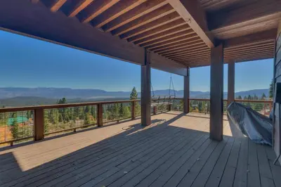 a large wooden deck with a hammock on it at Grand Vista Lodge by Tahoe Getaways - 5 BR with Stunning Views, Pool Table, Private Hot Tub & HOA Pool! in Truckee