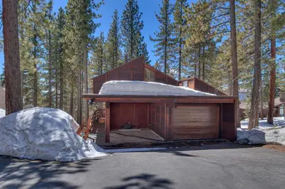 a wooden cabin in the woods with snow on the ground at Base Camp at Dollar Point by Tahoe Getaways - Hot Tub, Large Deck, Wood Fireplace, Short Drive to Ski Resorts! in Tahoe City