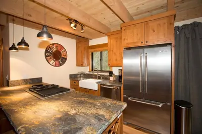 a kitchen with a stainless steel refrigerator and wooden cabinets at Away on Allenby by Tahoe Getaways - 3BR, Dog Ok, Close to Northstar! in Tahoe Vista