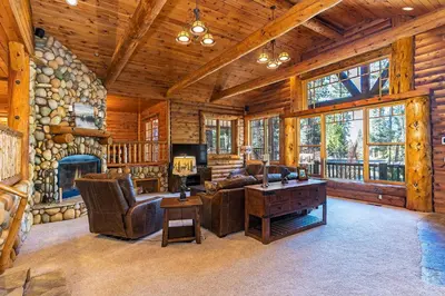 a living room with a large stone fireplace in a log cabin at 1138 Lakeshore - One-of-a-kind Lakeshore Boulevard log cabin in Incline Village