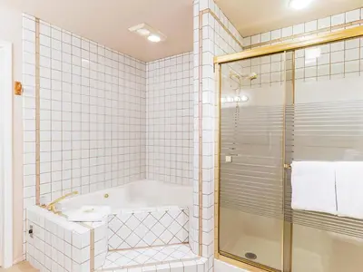 a white tiled bathroom with a tub and a shower at Mountain Shadows #172 - - pool in Incline Village