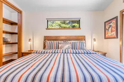 a bedroom with a bed with a striped comforter at Harmony at Tahoe Donner - Ultra Modern 4 BR, Hot Tub, Game Room, Amenity Access in Truckee