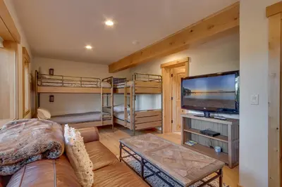 a living room with a couch and a tv and bunk beds at Huckleberry Haven by Tahoe Getaways - Luxury Lake View 4BR in North Lake with Private Hot Tub in Carnelian Bay