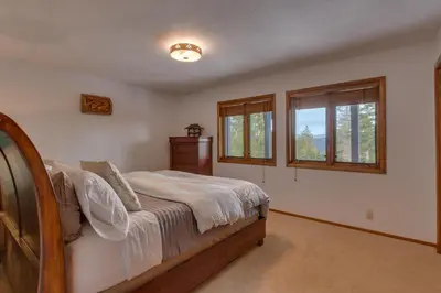 a bedroom with a bed and two windows at Kings Way Lake View by Tahoe Getaways - Spacious 4 BR w Private Hot Tub, Pool Table! in Tahoe Vista