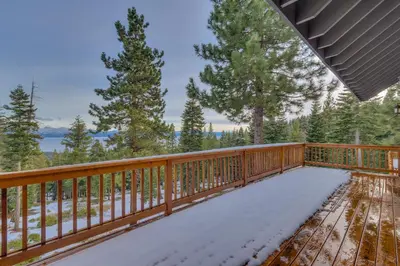 a wooden deck with snow on it at Kings Way Lake View by Tahoe Getaways - Spacious 4 BR w Private Hot Tub, Pool Table! in Tahoe Vista