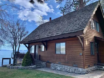 a log cabin on the shore of a lake at Lakeside Escape - Beautiful Lakefront, Pier, Wood Fireplace, Private Hot Tub in Tahoe Vista