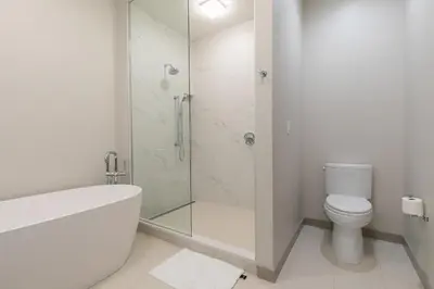 a white bathroom with a shower and a toilet at Larkspur Luxe at Northstar- 4 BR with Pool, Gym, Access - Walk to Village, Private Hot Tub in Truckee