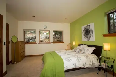 a bedroom with a bed with green walls and windows at Look Out Lodge - On North Shore w Lake View, Hot Tub, Pool Table and Pet Friendly in Kings Beach
