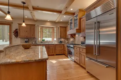 a kitchen with wooden cabinets and a stainless steel refrigerator at Majestic Woods at Tahoe Donner - High End Craftsman w Game Room, Hot Tub, Amenity Access in Truckee