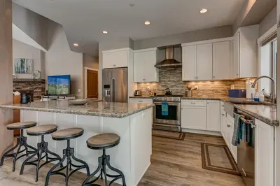 a kitchen with white cabinets and bar stools at Mountain Jewel in Tahoe Donner - Beautiful 4 Bedroom w Hot tub, Access to HOA Amenities in Truckee