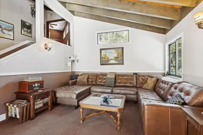 a living room with a leather couch and a table at On the Edge at Alpine Meadows - Fireplace- Mountain Views- Great Location! Shuttle Service! in Olympic Valley