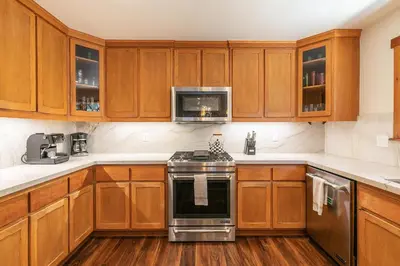 a kitchen with wooden cabinets and a stove top oven at Shady Pines at Tahoe Donner- Serene Forest Retreat, 2 Gas Fireplaces, Sauna in Truckee