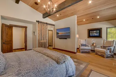a bedroom with a large bed and a living room at Sage Hen at Grays Crossing - Gorgeous 4BR 4BA Home w Private Hot Tub in Truckee