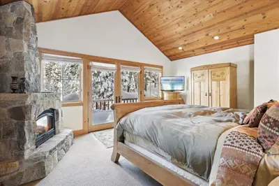 a bedroom with a large bed and a fireplace at Silverado Lodge at Palisades - 4BR w Private Hot Tub & Ski Shuttle in Olympic Valley