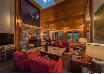 a living room with a fireplace and red chairs at Skidder - Luxury 3500 sqft - Northstar 4BR w Game Room, Sauna, & HOA Amenities in Truckee