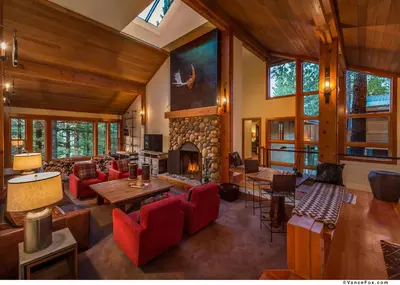 a living room with a fireplace and red chairs at Skidder - Luxury 3500 sqft - Northstar 4BR w Game Room, Sauna, & HOA Amenities in Truckee