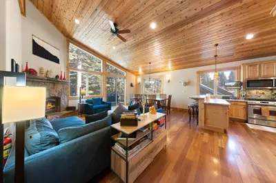 a living room with a blue couch and a kitchen at Skislope Manor - Spacious Tahoe Donner 4 BR with Gorgeous Home Theater and Hot Tub in Truckee