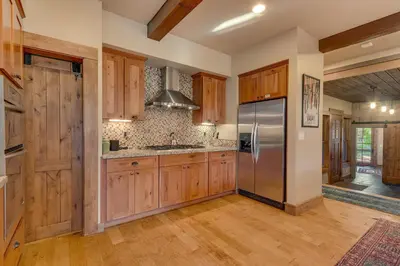 a kitchen with wooden cabinets and a stainless steel refrigerator at Norse Hall in Tahoe Donner - Gorgeous Home with Private Hot Tub and Gourmet Kitchen in Truckee