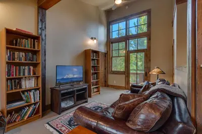 a living room with a leather couch and a television at Norse Hall in Tahoe Donner - Gorgeous Home with Private Hot Tub and Gourmet Kitchen in Truckee