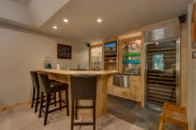 a kitchen with a counter and a bar with stools at High Altitude at Tahoe Donner - Huge 4 BR with Private Hot Tub, Pool Table, Ping Pong, HOA Amenities in Truckee