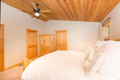 a bedroom with a white bed with a wooden ceiling at Interlaken on the West Shore by Tahoe Getaways - Pet Friendly 3BR, Close to Skiing & Walk to the Lake! in Homewood
