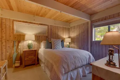 a bedroom with a bed and two lamps and a window at Cozy Wood Cabin- Updated- Hot Tub- Fireplace- Backs to Forest in Carnelian Bay