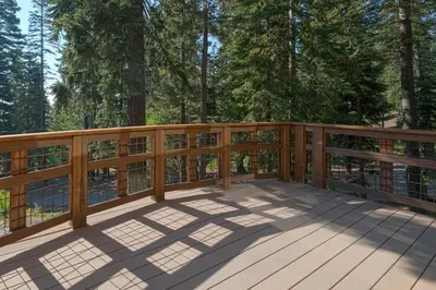 a wooden deck with trees in the background at North Shore Bliss by Tahoe Getaways - 3 BR plus loft & Private Hot Tub in Carnelian Bay