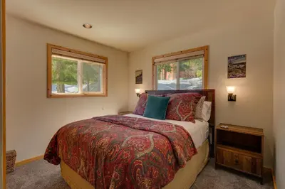 a bedroom with a bed and two windows at Piney wood - Quiet 2 BR Loft w Private Hot Tub in Carnelian Bay