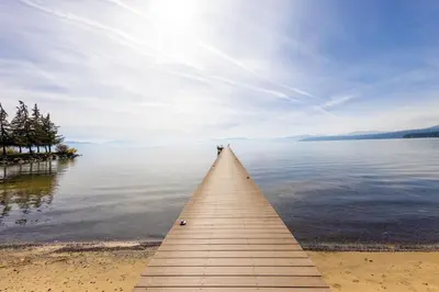 a wooden pier stretches out over a body of water at Sandy Cove on the North Shore -Lakeside Cottage with Pier Beach, and HOA Amenities in Tahoe Vista