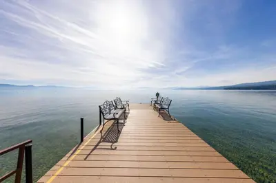 a row of chairs sitting on a dock on the water at Sandy Cove on the North Shore -Lakeside Cottage with Pier Beach, and HOA Amenities in Tahoe Vista