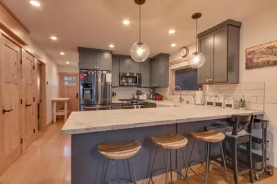 a kitchen with a large island with bar stools at Olympic Valley Hideaway - Newly Remodeled Cabin with Private Hot Tub in Olympic Valley