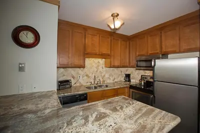 a kitchen with wooden cabinets and a stainless steel refrigerator at Palisades Tahoe Ski Condo by Tahoe Getaways - Remodeled 2 BR, Walking Distance to Lifts & Village in Olympic Valley