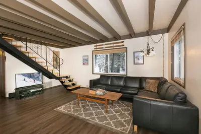 a living room with a leather couch and a staircase at Pineland Chalet in Tahoe City - Classic Cabin Wood Fireplace Dog Friendly in Tahoe City