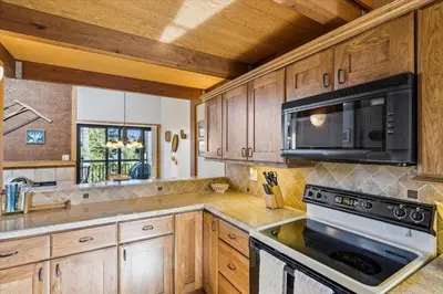 a kitchen with wooden cabinets and a microwave at Rocky Point # 4 - 2 BR Northstar Condo, Shuttle to Slopes, HOA Amenities! in Truckee