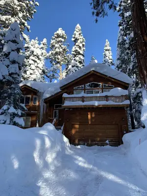 a log cabin covered in snow in the woods at Secret Garden Lodge - 4BR Walking Distance to the Lake, Hot Tub, Close to Ski Resorts! in Carnelian Bay