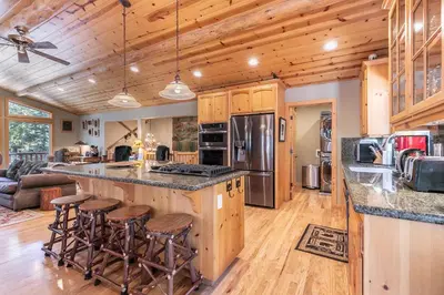 a large kitchen with wooden cabinets and bar stools at Secret Garden Lodge - 4BR Walking Distance to the Lake, Hot Tub, Close to Ski Resorts! in Carnelian Bay