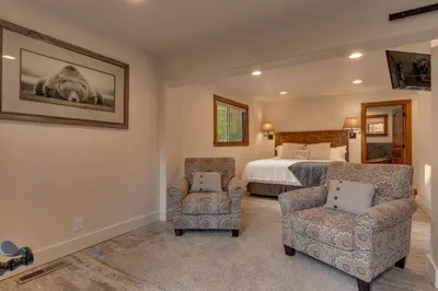 a bedroom with a bed and two chairs in it at Tahoe Rim Retreat - Spacious 4BR with Pool Table and Private Hot Tub - Pet Friendly! in Kings Beach