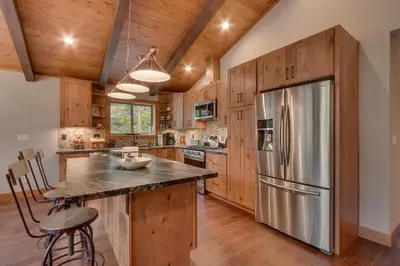 a kitchen with wooden cabinets and a stainless steel refrigerator at Skyland Jewel at Dollar Point - Luxury 3BR - Easy Winter Access in Tahoe City