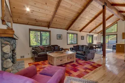 a living room with couches and a stone fireplace at Tahoe Woods by Tahoe Getaways - Pet Friendly Tahoe Park Cabin w Hot Tub, Fireplace, Near Skiing! in Tahoe City
