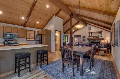 a kitchen and living room with a wooden table and chairs at Tahoe Woods by Tahoe Getaways - Pet Friendly Tahoe Park Cabin w Hot Tub, Fireplace, Near Skiing! in Tahoe City
