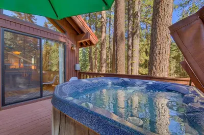 a hot tub on a deck with an umbrella at Tahoe Woods by Tahoe Getaways - Pet Friendly Tahoe Park Cabin w Hot Tub, Fireplace, Near Skiing! in Tahoe City