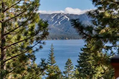 a view of a lake from between two trees at Appreciate this exclusive private penthouse located on Lake Tahoe in Crystal Bay