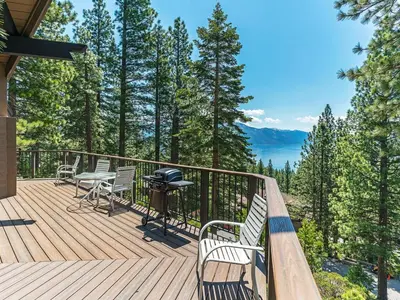 a wooden deck with chairs and a grill on it at Enjoy the brilliant views of Lake Tahoe from this mountainside Cabin in Incline Village