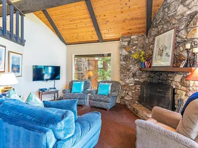 a living room with blue couches and a stone fireplace at Enjoy the brilliant views of Lake Tahoe from this mountainside Cabin in Incline Village