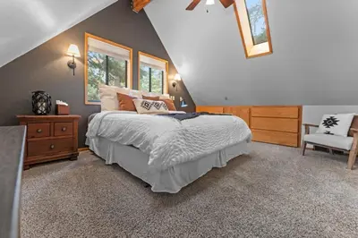 a bedroom with a large bed and a chair at Tranquil Tahoe A-Frame Walk to Beach in Tahoe Vista