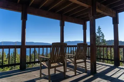 two chairs on a porch with a view of the mountains at Sierra Lake View at Rubicon by Tahoe Getaways - 3 BR, Panoramic Lake Views, Private Hot Tub & Private beach! in Tahoma