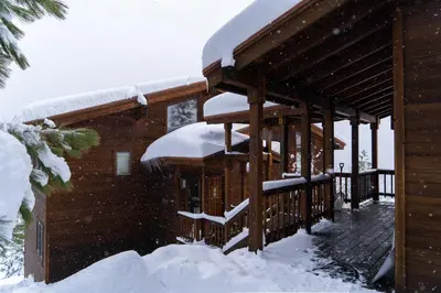 a cabin with snow on the roof of it at Sierra Lake View at Rubicon by Tahoe Getaways - 3 BR, Panoramic Lake Views, Private Hot Tub & Private beach! in Tahoma